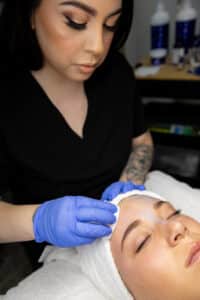 Esthetician preparing skincare products for facial treatment at Third Eye Beauty Lounge