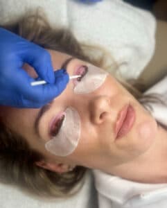 Client lying down during a lash lift appointment at Third Eye Beauty Lounge in Tempe, AZ. A lash artist is carefully applying lifting solution to the natural lashes using a silicone rod and precision tools.